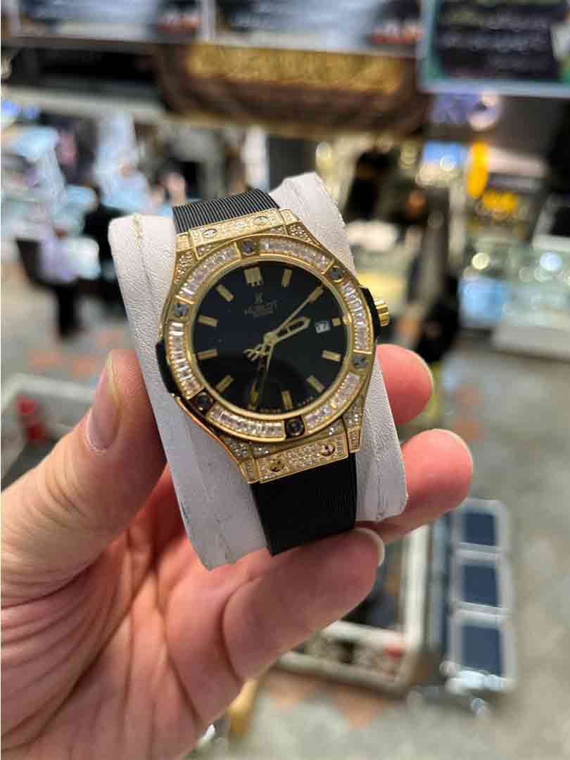 ساعت مچی زنانه هابلوت دورفول نگین بند مشکی قاب طلایی صفحه مشکی مدل Hublot Diamonds