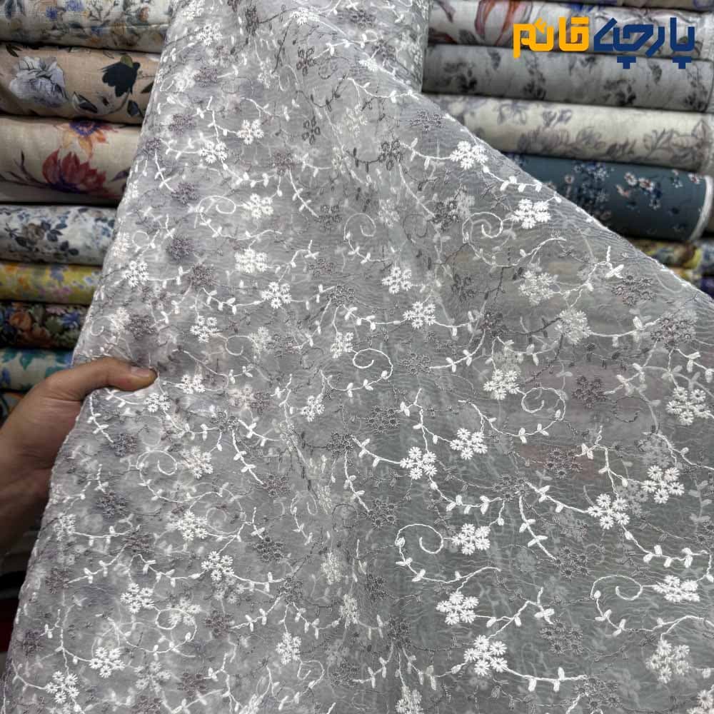 پارچه مجلسی تورکتان طرح گل متوسط و شاخه رنگ طوسی روشن و سفید زمینه اورگاندی کد۷۶۱۳