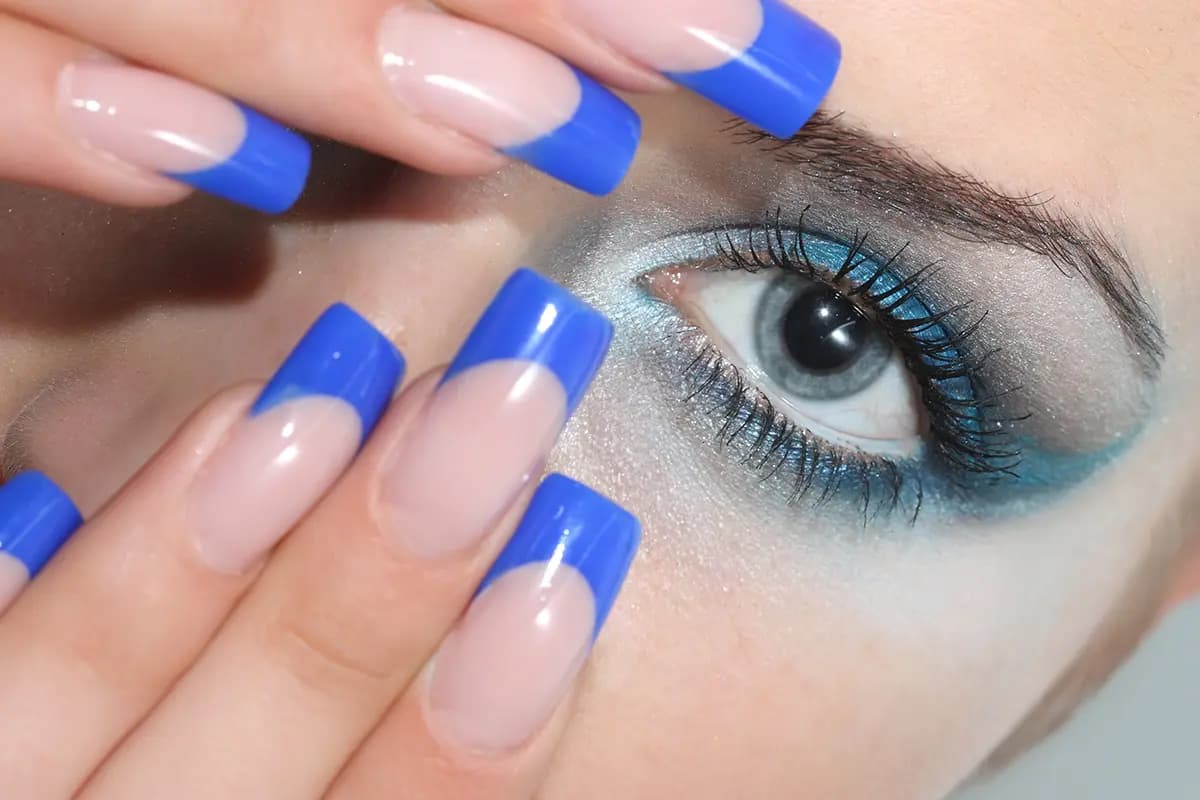 عکس استوک چشم آرایش‌ شده با سایه اسموکی آبی و ناخن فرنچ