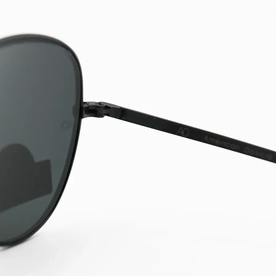 عینک آفتابی American Optical با فریم خلبانی، رنگ مشکی براق، عدسی جنس سنگ (شیشه) و دودی تیره مدل AO-1004 — تصویر ۵