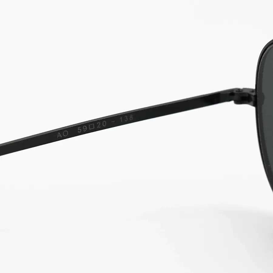عینک آفتابی American Optical با فریم خلبانی، رنگ مشکی براق، عدسی جنس سنگ (شیشه) و دودی تیره مدل AO-1004 — تصویر ۷