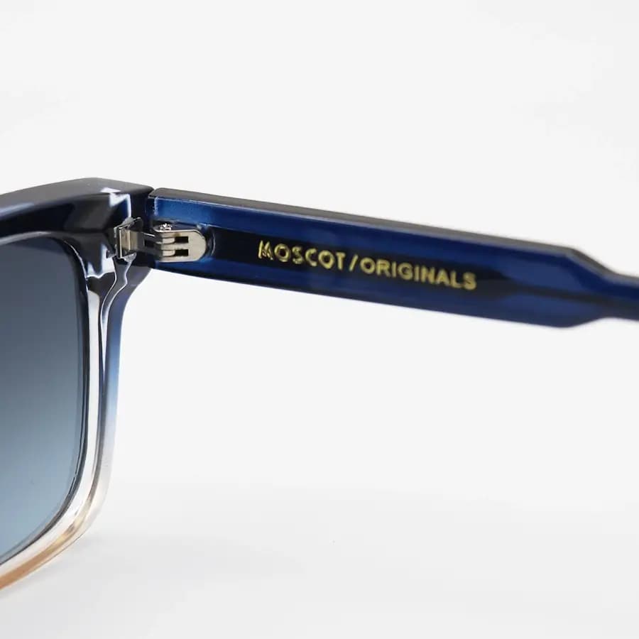 عینک آفتابی MOSCOT با فریم مستطیلی، رنگ آبی و قهوه‌ای، دسته سیم‌دار و لنز دودی هایلایت و پلاریزه مدل P1210 — تصویر ۴