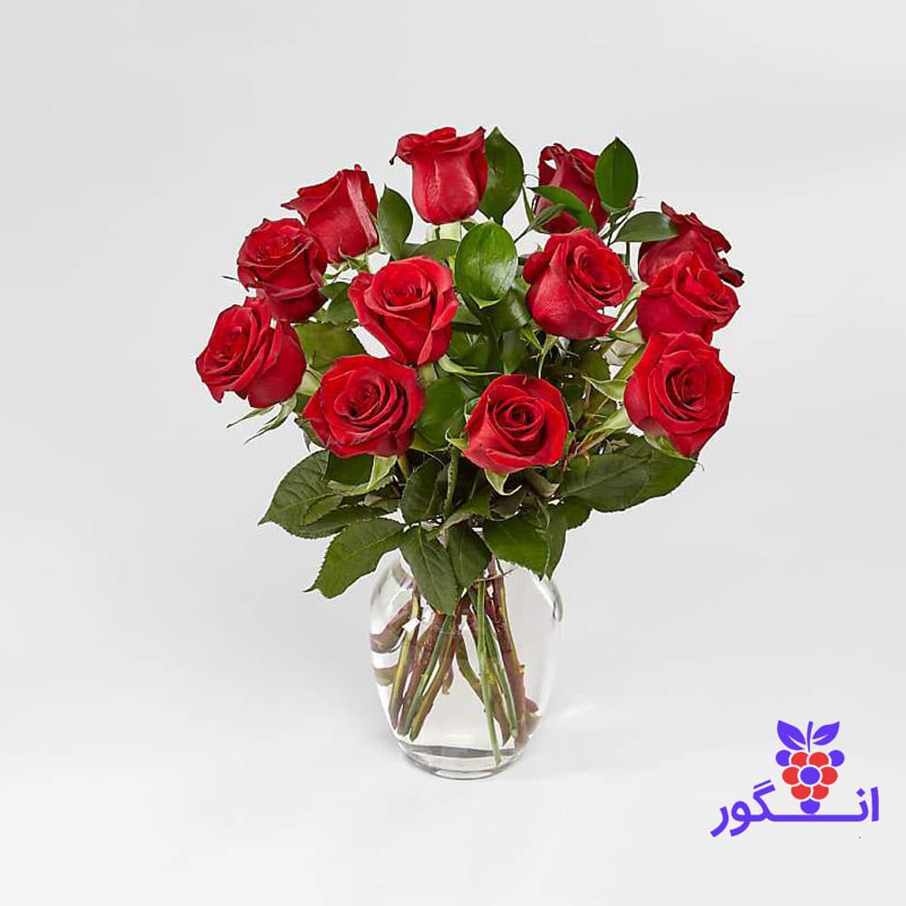 دسته گل رز قرمز ۱۲ شاخه به همراه گلدان شیشه‌ای