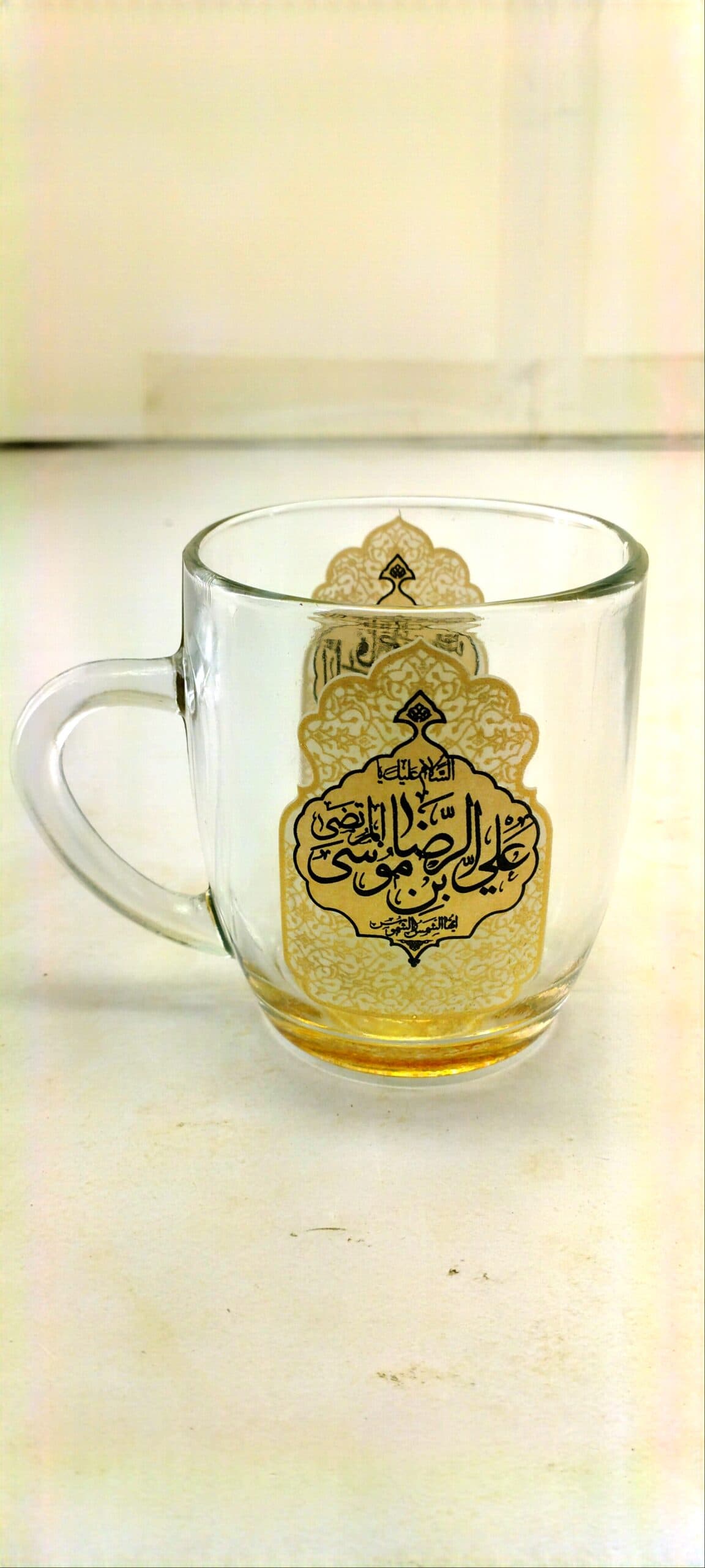 ۱۰۲۸۰۴-لیوان شیشه ای دسته دار ماگ شفاف طلایی یا علی بن موسی الرضا ع و یا فاطمه المعصومه س