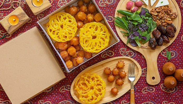 تصویر پس زمینه نمای بالا سفره افطار با زولبیا و بامیه